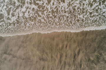 Close-Up Aerial View of Ocean Waves Reaching Sandy Beach