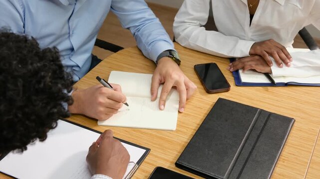 Detailed close-up of handwritten notes and documents on a meeting table, professional hands taking notes, representing strategy, productivity, collaboration, and business planning