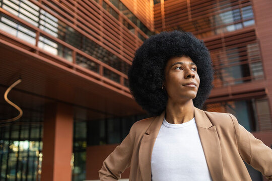 Person in brown blazer standing by modern building