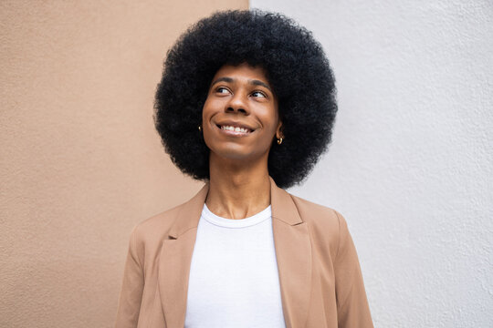 Person smiling in a brown blazer against a two tone wall