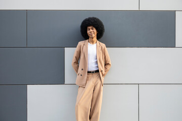 Person in brown blazer standing against modern design wall