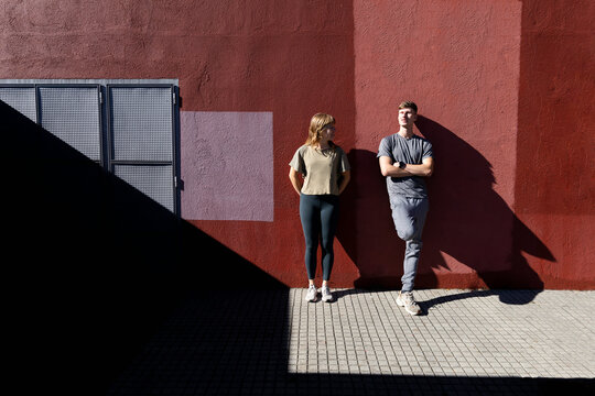 Autumn siblings in urban body poses against red wall