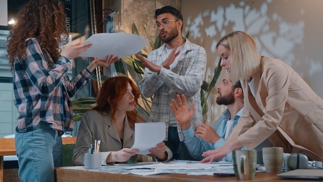 Five people feeling irritation arguing in casual informal business conference meeting throwing papers documents work team misunderstanding problem paperwork chaos Caucasian man boss leader frustrated