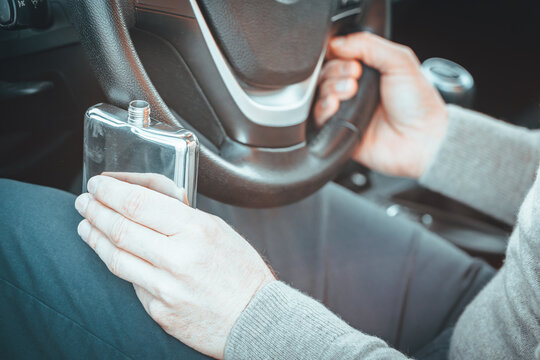 Drinking and driving, drunk driver, sobriety check of drivers. A man is driving a car, holding a bottle of alcohol in one hand and the steering wheel in the other. Road safety concept