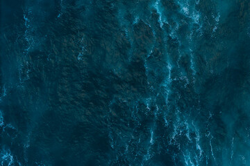 Aerial top down view of Atlantic oceanic waves rolling and creating foam patterns, Drone filming breaking surf with foam in Atlantic ocean © Leonid