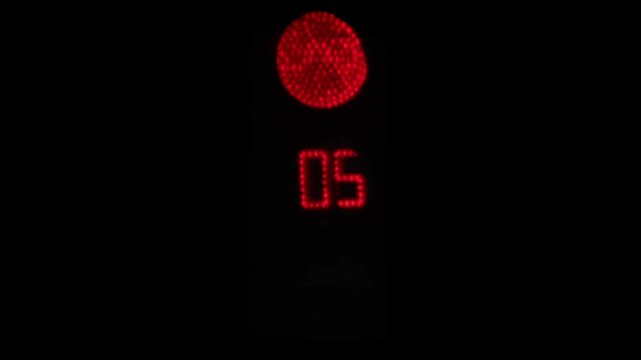 Real road traffic light with countdown timer, telephoto close-up on black background, LED signal looping, slight atmospheric turbulence, no people
