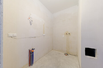 Unfinished bathroom interior with exposed pipes and wires