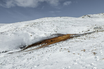 Geothermal steam rising in snowy Reykjadalur Valley, Iceland.