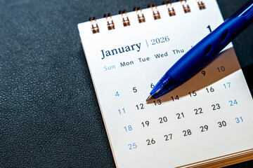 A close-up of a calendar page displaying January 2026, with emphasis on the date 12. A blue pen is...