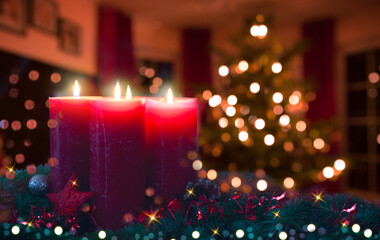 Four burning red Advent candles isolated on glowing Christmas tree background.