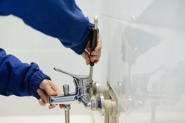 Plumber repairing a faucet with tools in a modern bathroom setting