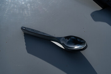 Stack of metal spoons with sky reflections placed on light surface.