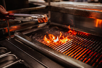 A professional chef is grilling delicious meat in a restaurant kitchen 