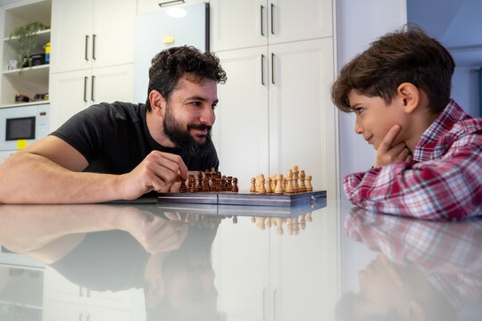 father and son playing chess at home