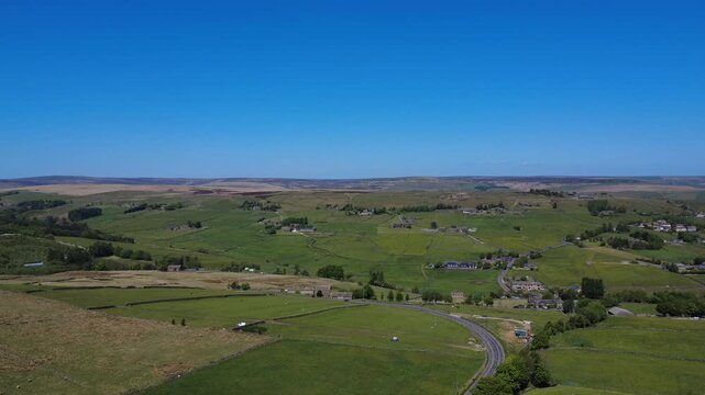 aerial panoramic view of west yorkshire landscape between blackshaw head and colden near Hebden Bridge showing farms houses and meadows in spring sunlight