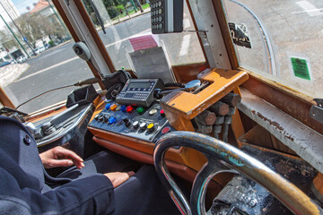 Close-up view of a tram driver's hands operating the vintage controls and dashboard inside the historic Tram 28 in Lisbon, Portugal.