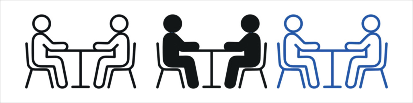 Two individuals engaged in a discussion or interview sitting across a table
