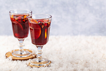 Mulled wine. Refreshing beverage served in elegant glasses, featuring colorful fruit garnishes, placed on textured snow, creating vibrant and inviting atmosphere for any occasion