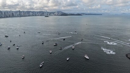 Balneario Camboriu, Santa Catarina, Brazil. 16.12.2024. An aerial view showcasing several boats sailing on the vast ocean, with a cityscape visible on the horizon.
