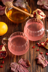 Autumn Beverage: two Cups ofPomegranate Tea with Lemon and Ginger on Rustic Table