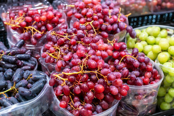 Organic market. Fresh assorted grapes in clear containers are beautifully displayed at market, showcasing vibrant colors and textures, inviting customers to enjoy delicious and healthy fruit selection