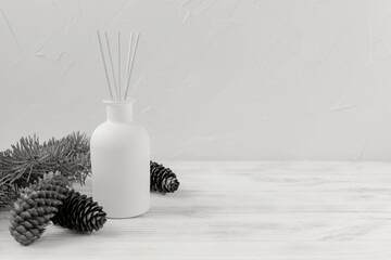 Perfumes for home. Aromatic reed diffuser on Gray background with Christmas tree branch and cones. Concept of tranquility, relaxation and enjoyment. Demonstrating color of 2026 year, Cloud, Dancer