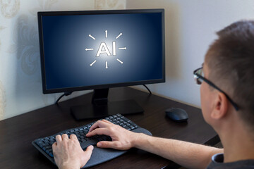 Remote work from home. Young man focused on computer screen displaying artificial intelligence graphics seated at sleek desk in contemporary workspace, surrounded by technology and innovation elements