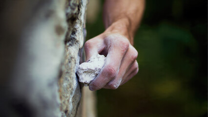 Climber hand gripping rock, covered in chalk