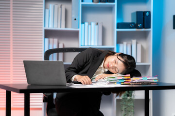 Exhaustion in the Office: An office worker, overwhelmed by the demands of the day, finds temporary respite, her head resting on a stack of documents as a laptop sits nearby.