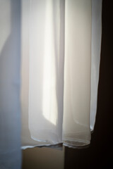 Light airy curtain gently swaying in a soft breeze, allowing natural light to filter through in a serene indoor space. An element of tranquility and elegance enhances any room's atmosphere.