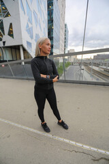 Woman in sportswear standing outdoors in a modern urban environment