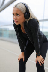 Woman wearing headphones resting outdoors after an intense workout session