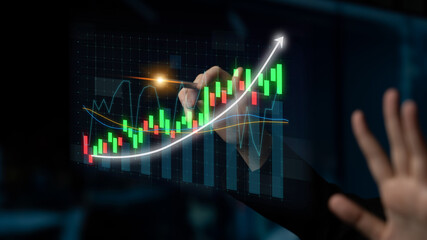 A person draws a financial chart on a transparent screen with vibrant growing graphs, symbolizing data analytics and investment growth in a professional setting. Impute