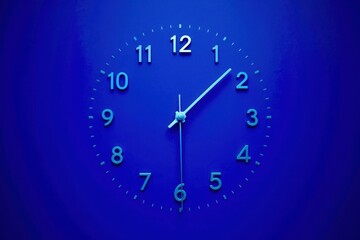 A blue clock with the hands at 10 and 2