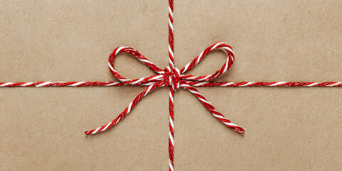 Red and White Christmas String Tied in Bow on Kraft Paper Background Minimal Flat Lay