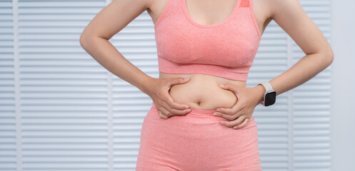 Body Assessment: A person in workout clothes evaluates their body, highlighting areas for improvement, a moment of personal self-reflection and empowerment.