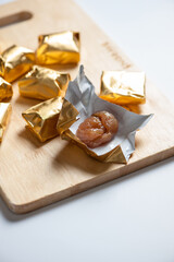 Wrapped Chestnut Candy on Wooden Board