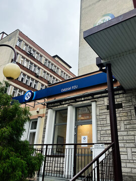 Office building entrance of a PZU branch with blue sign and glass doors in Tarnow, Poland.