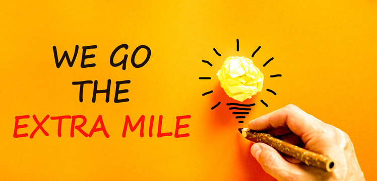 Support, help we go the extra mile symbol. Concept words We go the extra mile on beautiful paper. Beautiful orange background. Businessman's hand. Business we go the extra mile concept. Copy space.