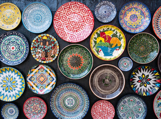 Lots of decorative color ceramic plates with traditional Uzbek ornaments hanging on wall . Not ai