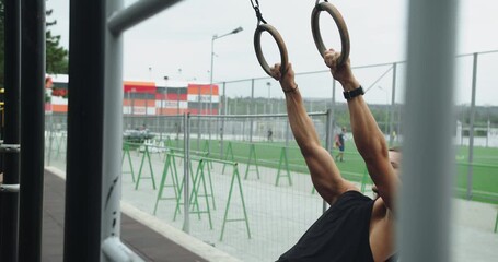 Man building arm muscles with exercise. Fitness Sport Street Workout. Muscle Up In Public Gym. Outdoors gym. Sportive fit man doing fitness exercises on sports rings. gymnastic rings.