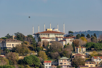 Scenic Istanbul cityscape featuring the iconic Sultan Ahmed Mosque rising above hillside homes and greenery, showcasing historic architecture, urban life, and travel atmosphere in Turkey.