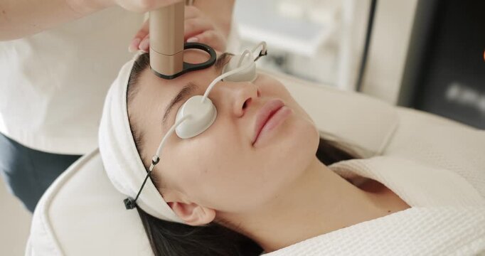 Beauty woman with protective glasses,Close up of a young girl getting laser face treatment in a medical center,Skin rejuvenation concept.Beautician cosmetologist doing procedure fractional microneedle
