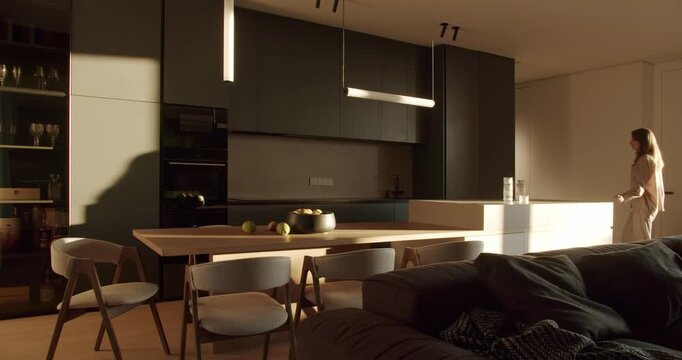 Modern kitchen interior with dark green cabinets, white countertop, and wooden dining table. Sunlight streams through the window, illuminating the room.