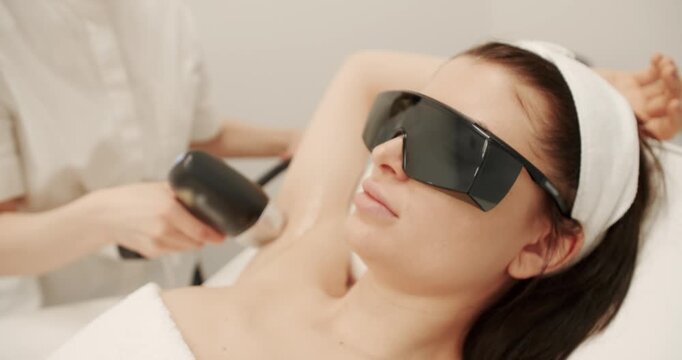 Beautician removes hair on beautiful female armpit using a laser. Hardware removal of hair on the legs in a beauty salon. Laser epilation cosmetology. hair removal procedure, Laser procedure at clinic