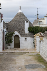 intimate street view of iconic trulli houses in alberobello, italy. the distinctive conical stone roofs and white walls create a captivating mediterranean scene