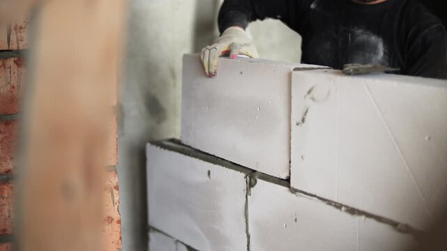 Worker installing aerated concrete blocks with mortar