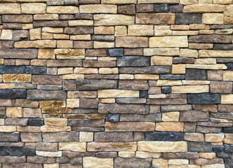 A stacked wall of rectangular stones in various earthy tones and textures creating a rustic facade