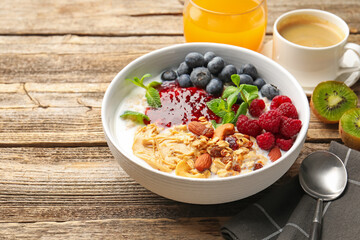 Healthy breakfast. Oatmeal with nuts, berries and yoghurt in bowl on wooden table, closeup. Space for text