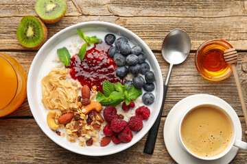 Healthy breakfast. Oatmeal with nuts, berries, yoghurt, coffee and orange juice on wooden table, flat lay